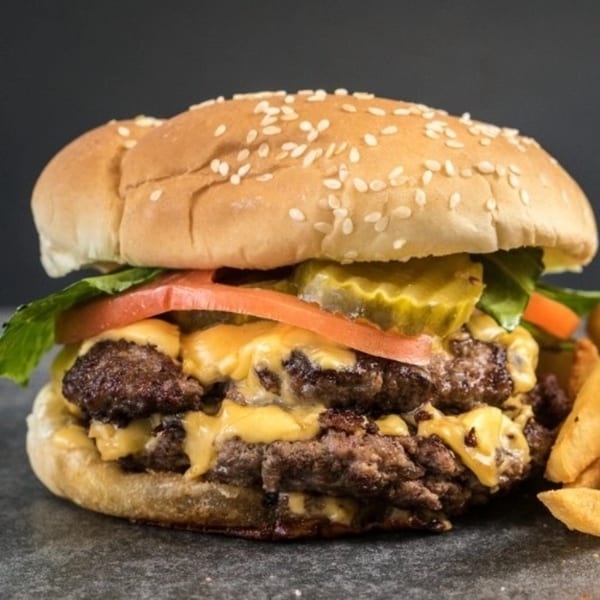 Deens Cheesesteak & Pizza's double cheeseburger with melted cheese, lettuce, tomato, and pickles.